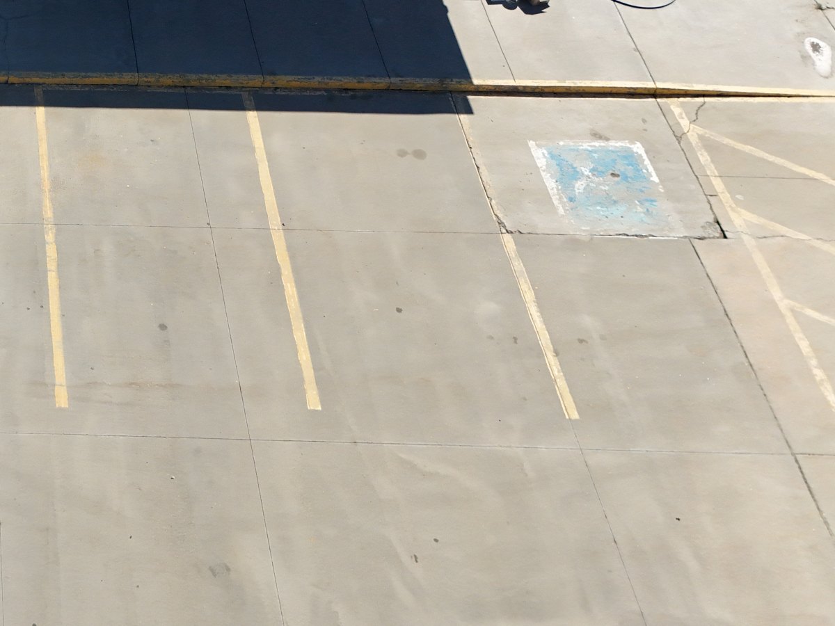 Drone view of faded parking lot stripes and accessible parking symbol before striping